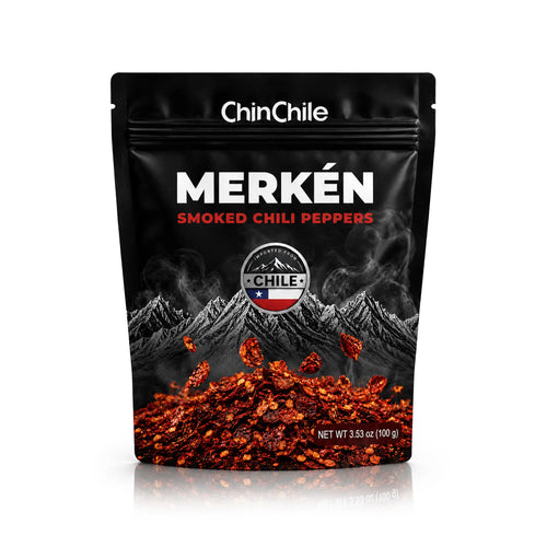 A black stand-up pouch of ChinChile Merkén Smoked Chili Peppers, featuring a graphic of snow-capped mountains and a pile of red chili flakes, on a white background with a soft reflection.