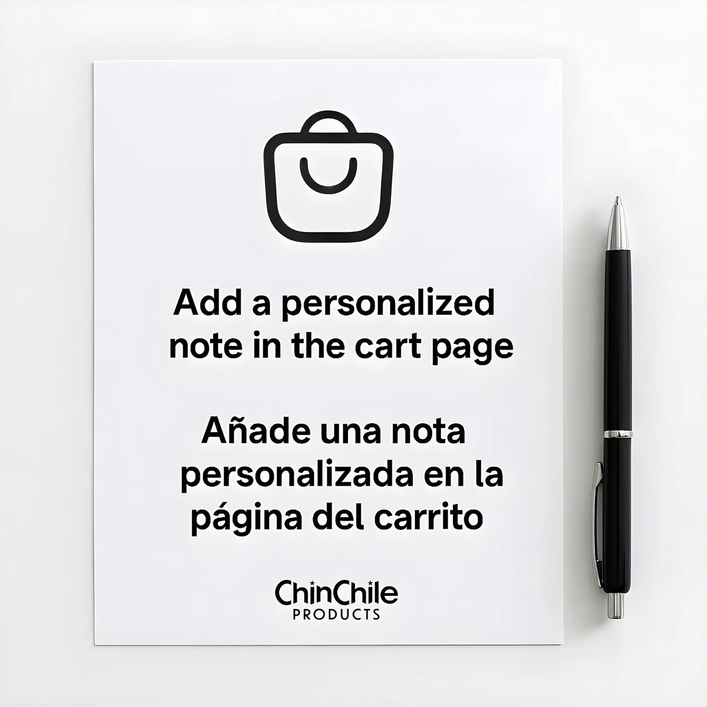 Hoja de papel blanca con un bolígrafo negro al lado, en la que se lee el mensaje «Añade una nota personalizada en la página del carrito» y su traducción al español: «Añade una nota personalizada en la página del carrito».