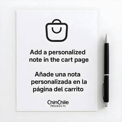 Hoja de papel blanca con un bolígrafo negro al lado, en la que se lee el mensaje «Añade una nota personalizada en la página del carrito» y su traducción al español: «Añade una nota personalizada en la página del carrito».