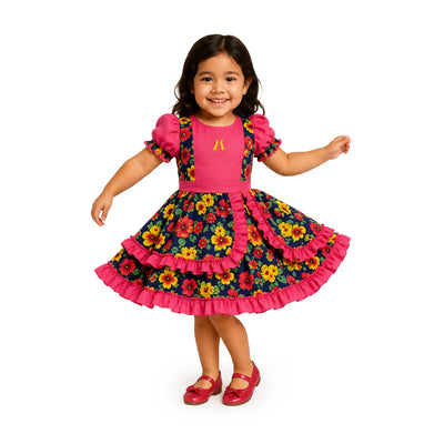 Girl wearing the Traditional Pink Floral Girls Vestido Huasa Chinita, a Chilean cueca dress with a pink bodice and navy floral skirt with pink ruffles.