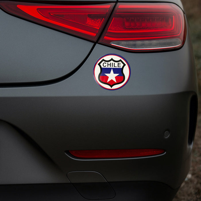 3x3 round Chilean badge sticker on the back of a gray car.